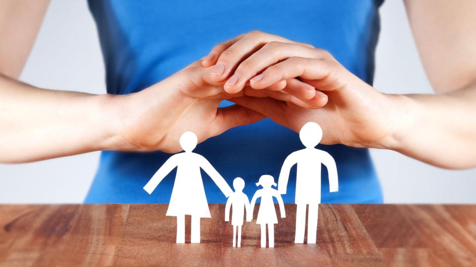 EIne Frau hält schützende Hände über eine Schrenschnittfamilie