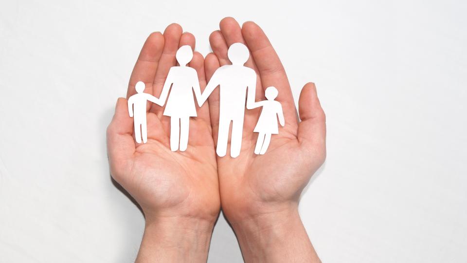 Eine Scherenschnittfamilie liegt in Händen
