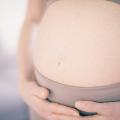 Hochschwangere Frau hält sich unter dem Bauch fest